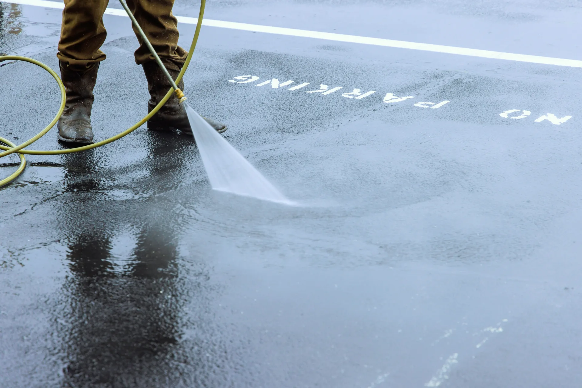 Operator pressure washing a commercial car park pavement