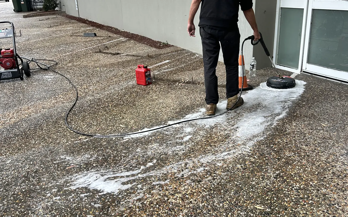 Universal Facilities Management operator pressure washing a commercial car park with a surface cleaner