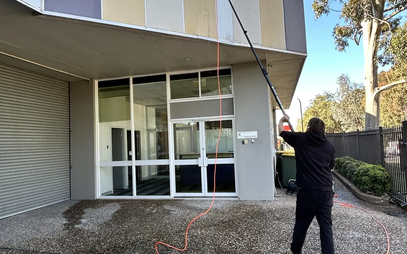 Universal Facilities Management operator cleaning a commercial building facade with a water-fed pole