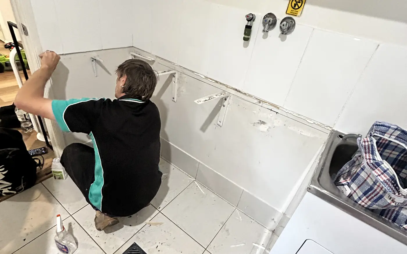 Universal Facilities Management tradesperson fitting wall brackets during a utility room repair